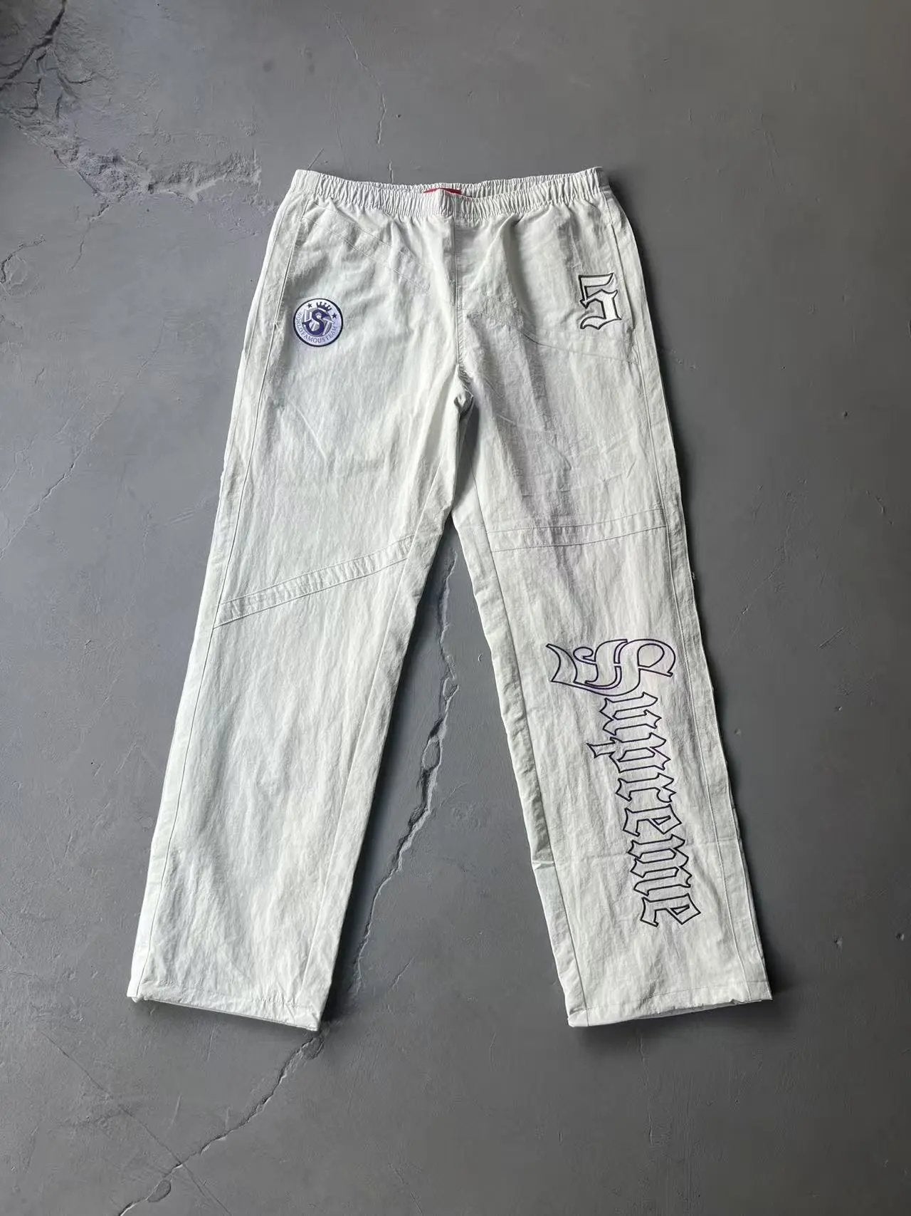 White pants with branding on a gray surface