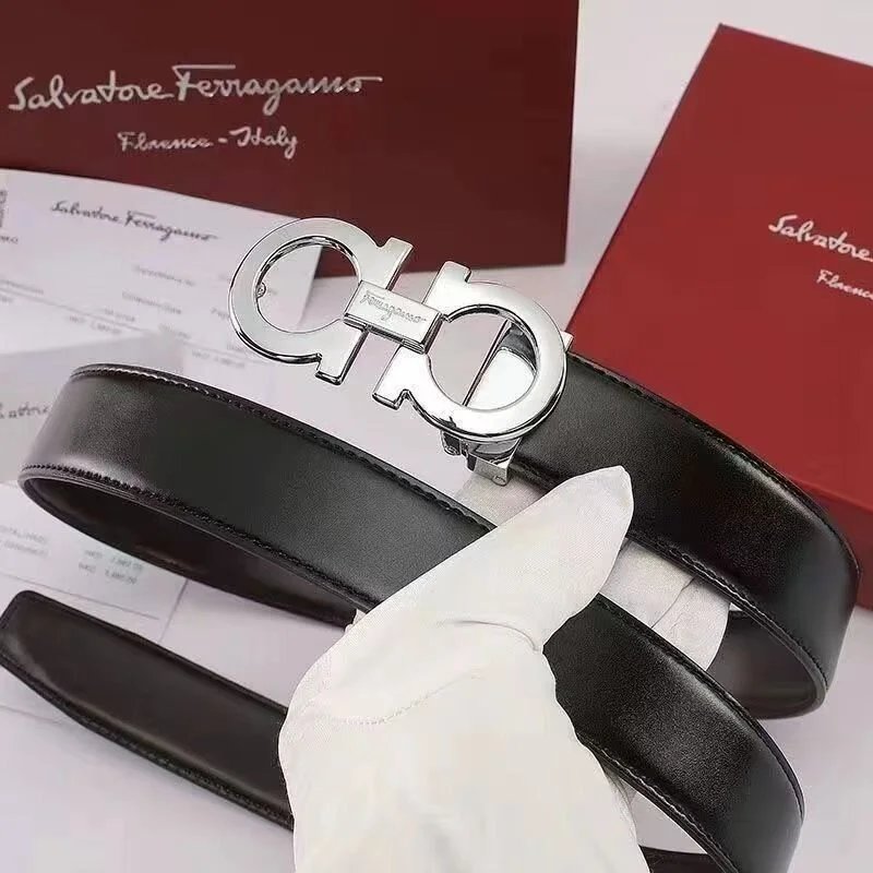 Black belt with Ferragamo logo on a white surface, with a Ferragamo box and paper in the background.