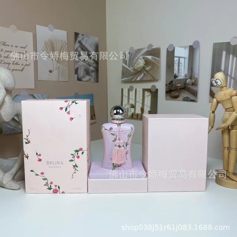 Perfume bottle with floral design and packaging on a white surface, with a blurred background.