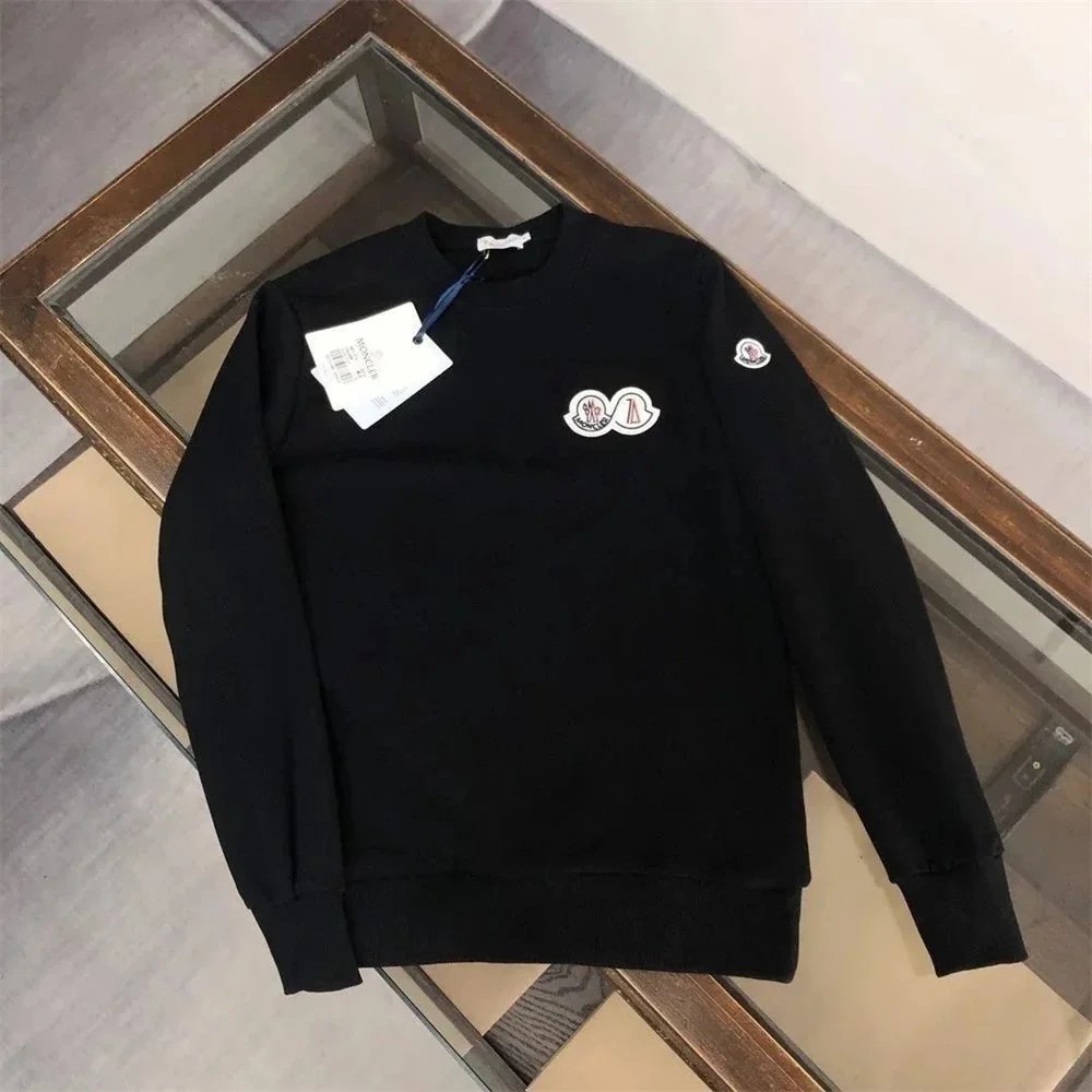 Black sweater with white logo on a wooden surface