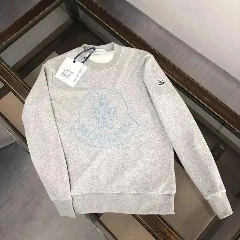 Light gray sweatshirt with brand tag on a wooden surface