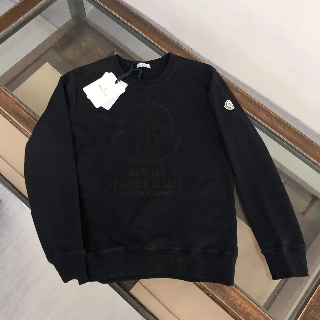 Black sweatshirt with a logo on a glass surface