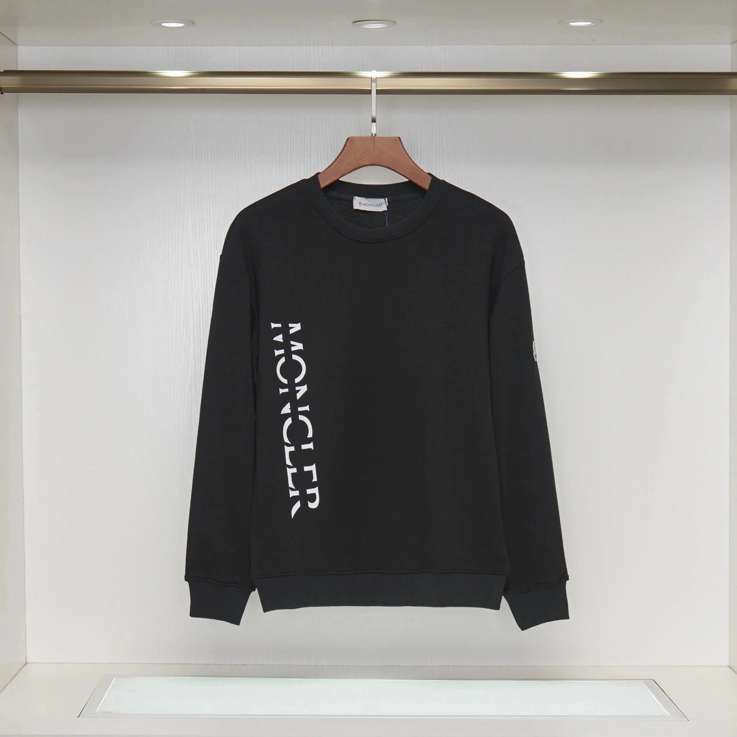 Black Moncler sweatshirt on a hanger against a white background