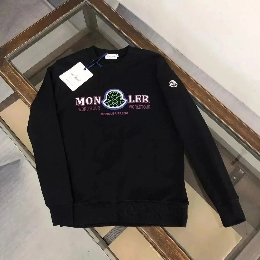 Black sweatshirt with 'MONCLER' branding on a wooden surface