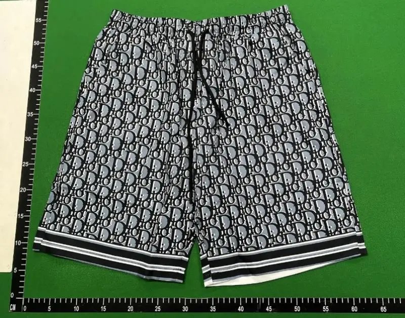 Black and white patterned shorts on a green background with a ruler for size reference.
