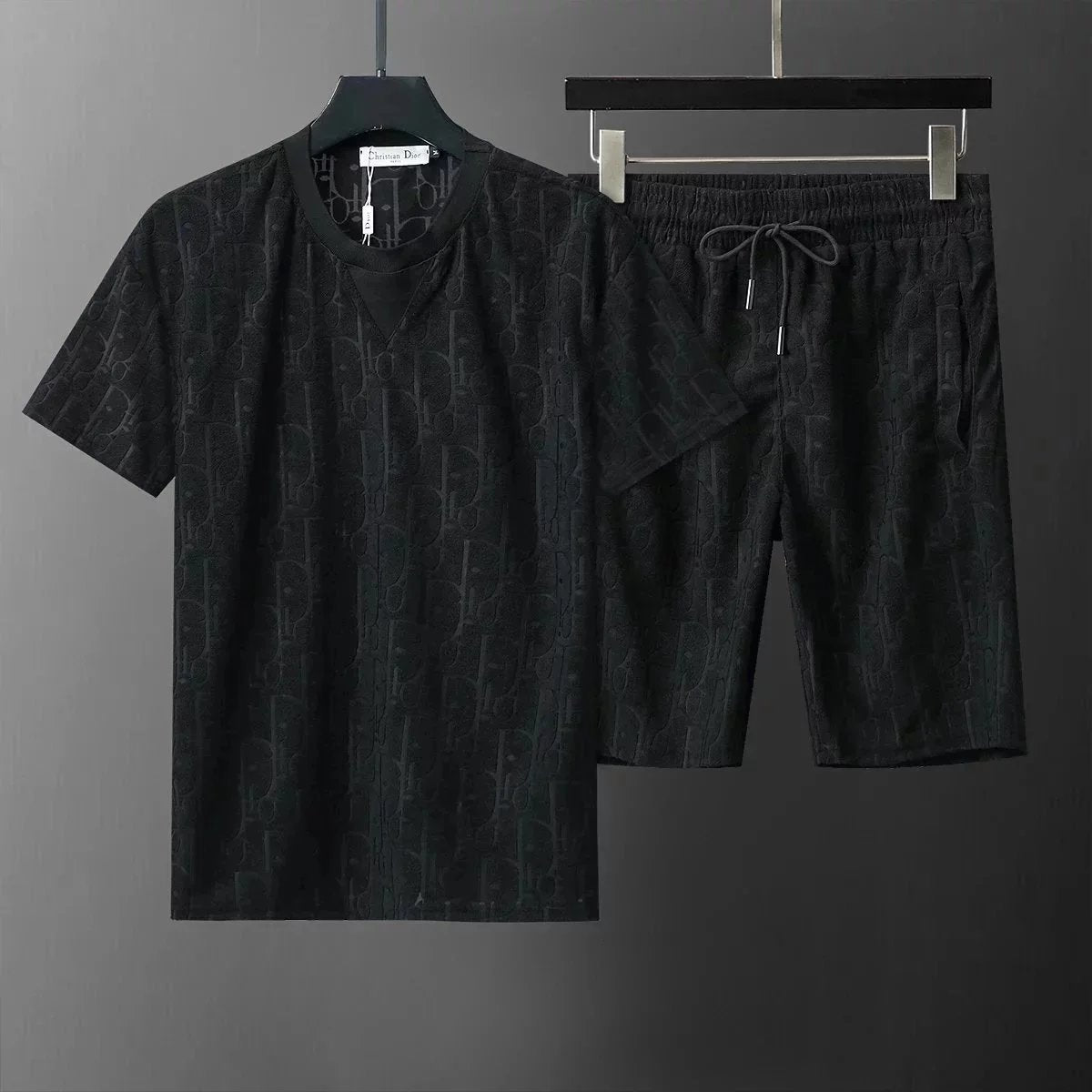 Black t-shirt and shorts set on hangers against a gray background