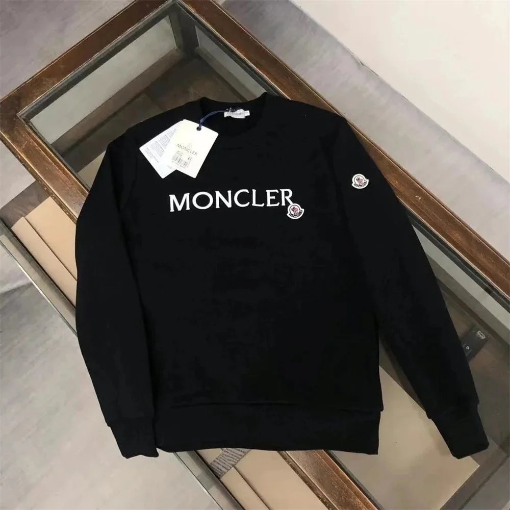 Black Moncler sweatshirt with a tag on a reflective surface