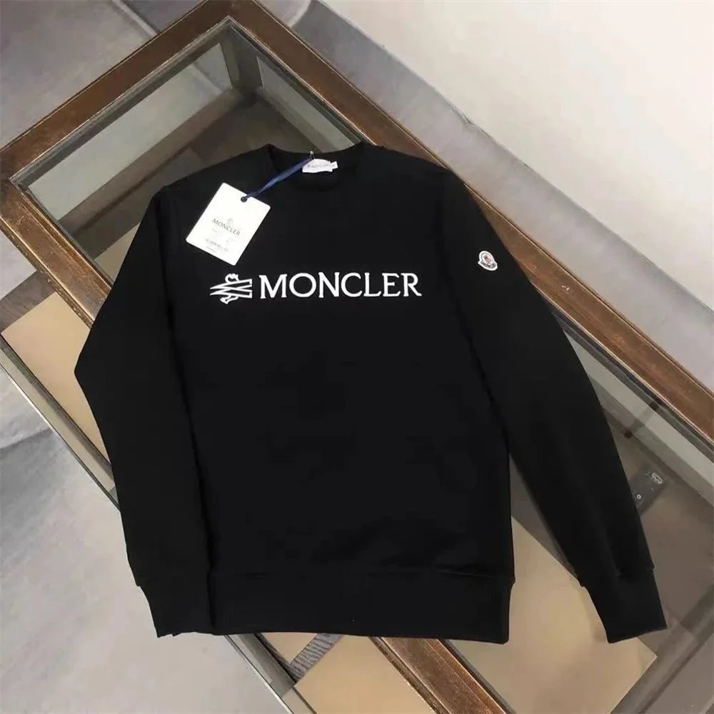 Black Moncler sweatshirt with a tag on a wooden floor.