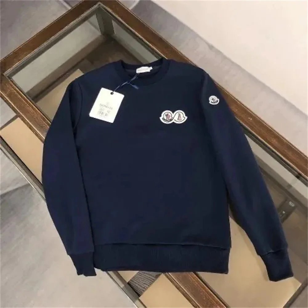 Navy blue sweatshirt with a small white logo on a gray surface