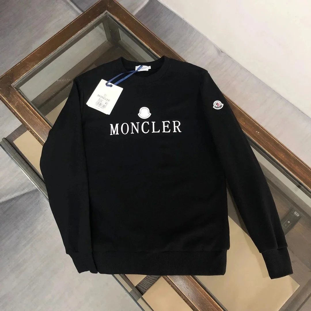 Black Moncler sweatshirt with a tag on a wooden surface