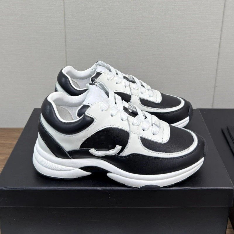 Black and white sneakers on a black platform with a gray wall background