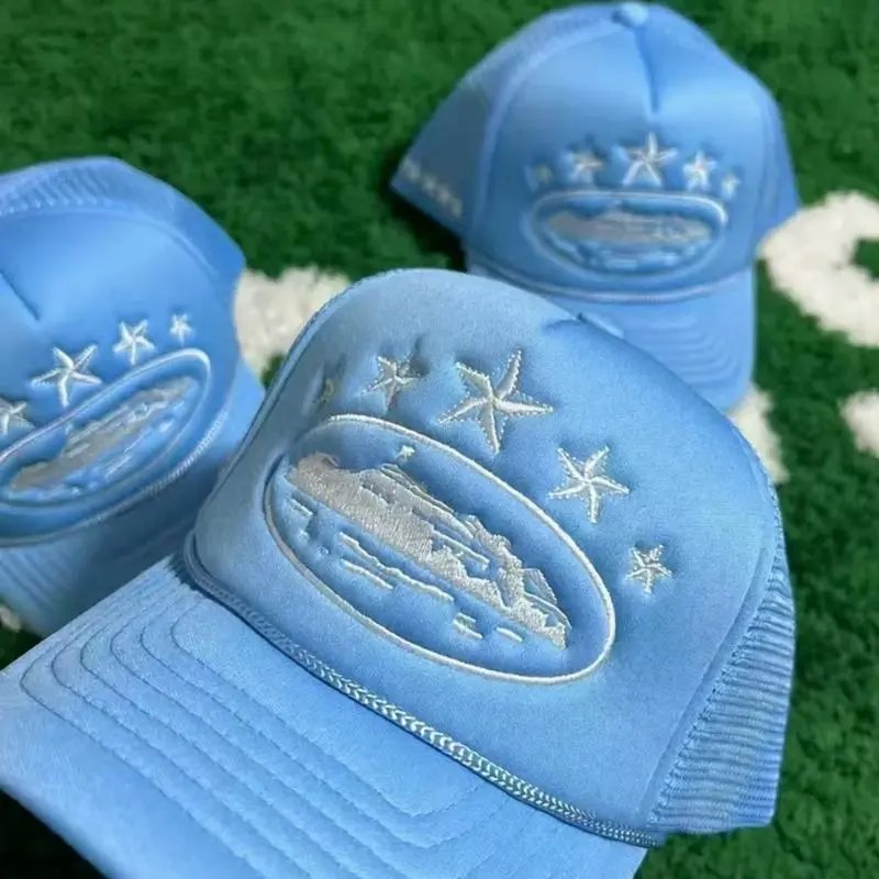 Two blue caps with embroidered designs on a grassy background
