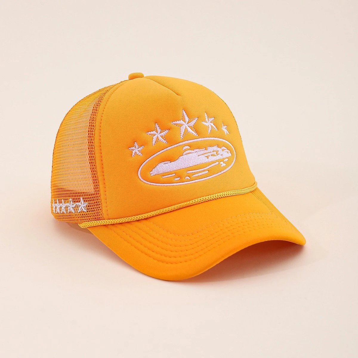 A bright orange-yellow trucker cap with white embroidered stars and a boat graphic on the front, set against a solid light beige background.
