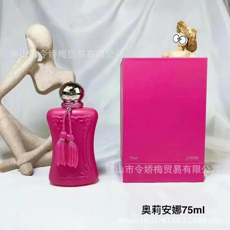 Pink perfume bottle with tassels and matching box on a white background