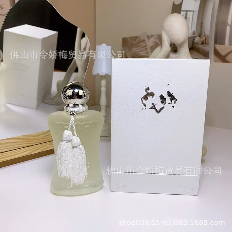 Perfume bottle with tassels and packaging box on a white surface