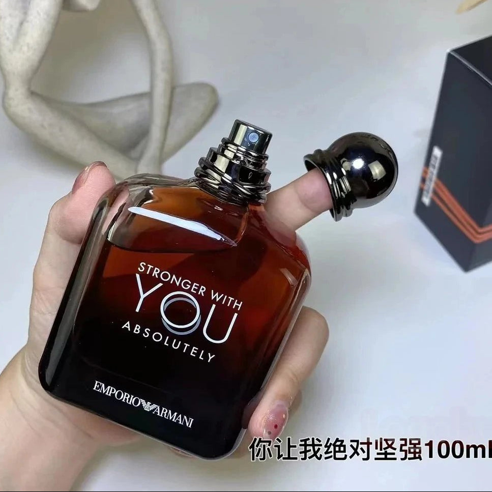 Perfume bottle held by a hand with 'Stronger with You Absolutely' text, brand visible