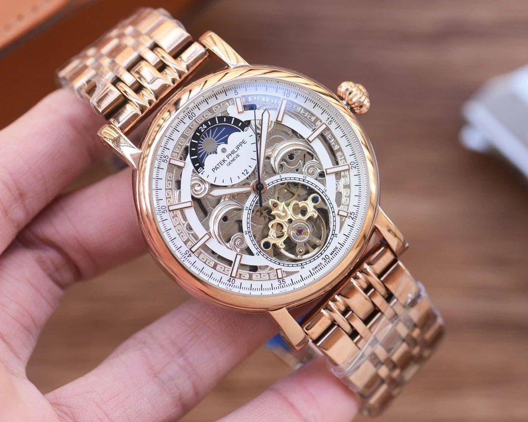 Rose gold wristwatch with intricate design held in a hand against a blurred background