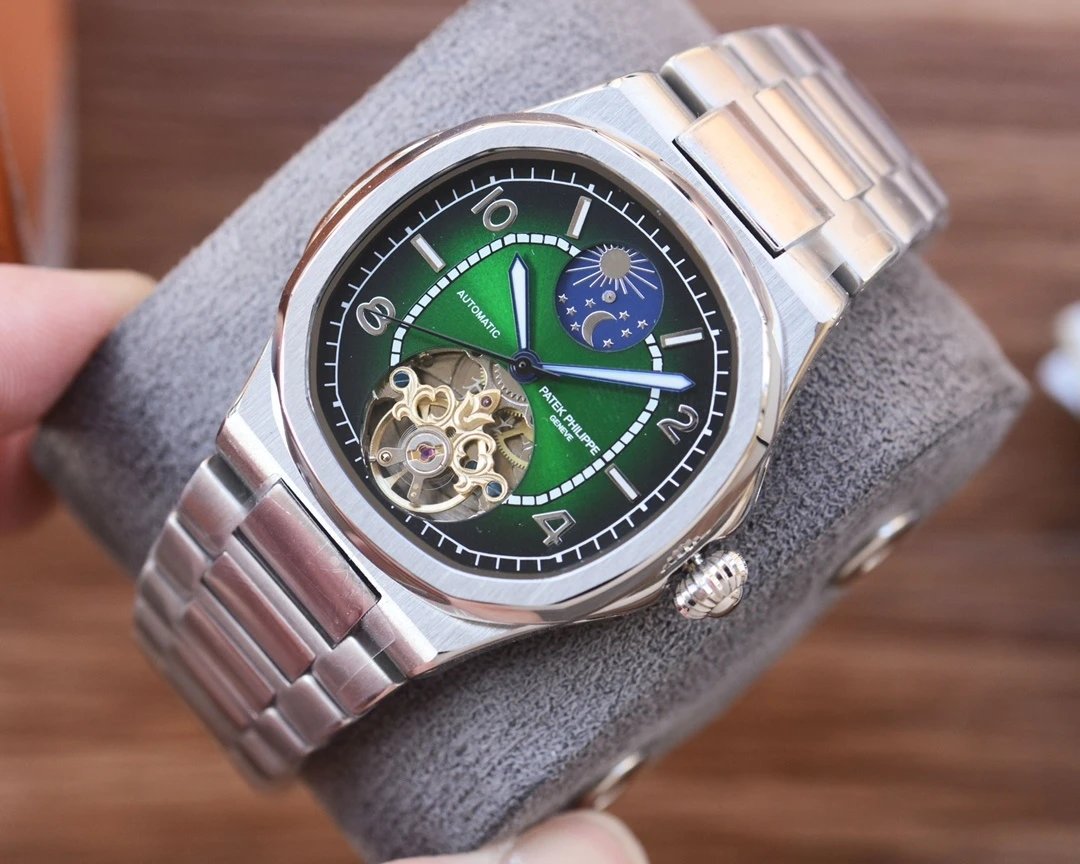 Silver watch with a green face held by a hand on a wooden surface