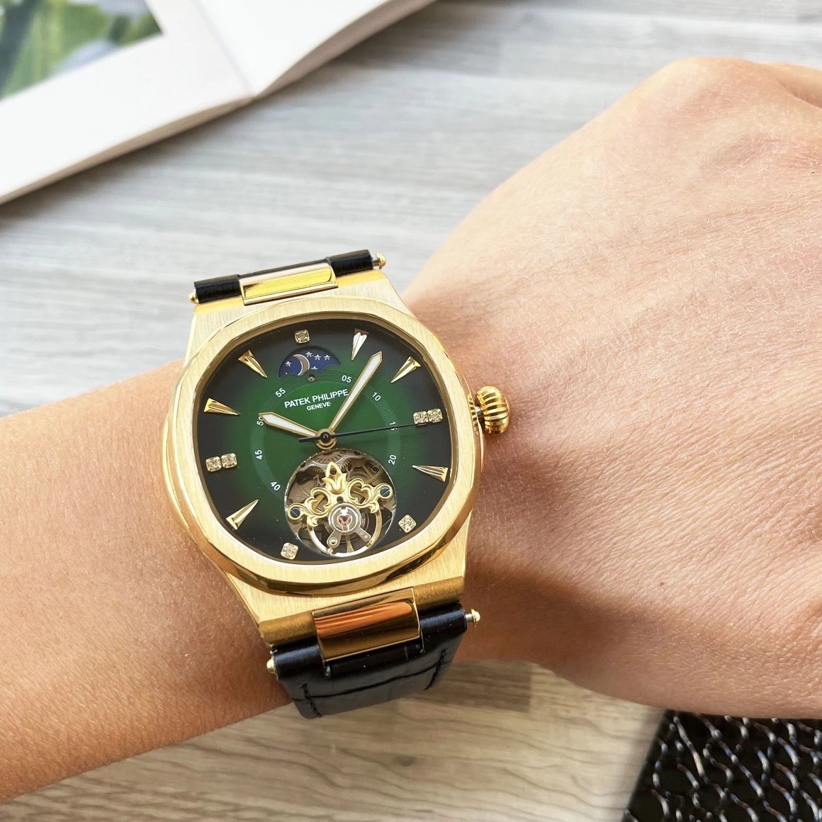 Gold wristwatch with green face on a wrist, blurred background
