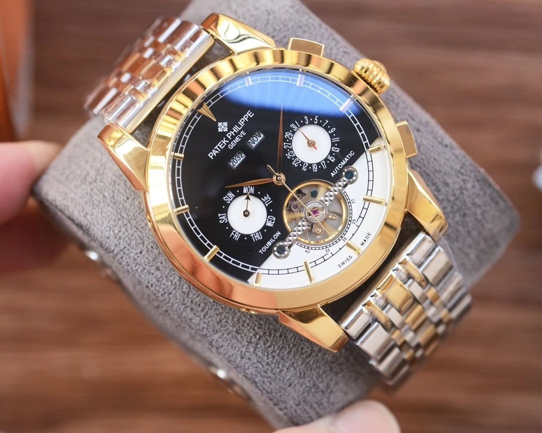 Luxury watch with gold and silver band held by a hand on a wooden surface