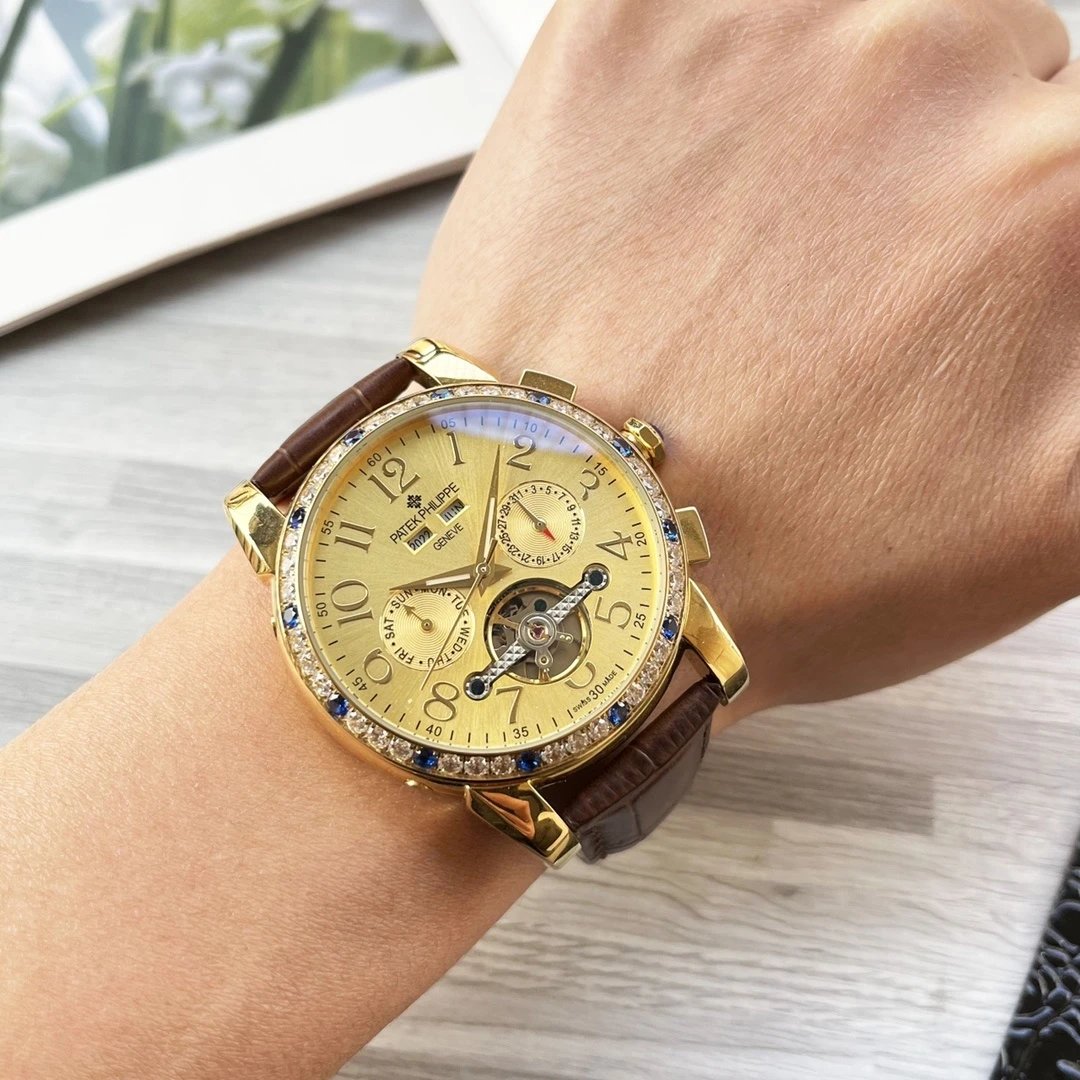 Gold wristwatch with a brown leather strap on a wrist, with a blurred background.