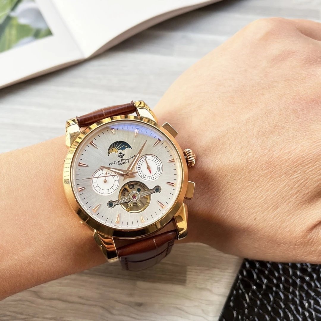 Gold wristwatch with brown leather strap on a wrist, blurred background