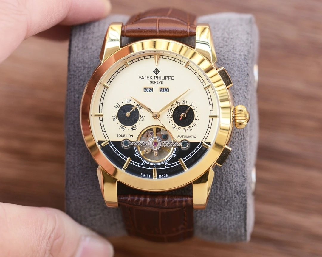 Gold wristwatch with brown leather strap on a gray cushion, held by a hand.