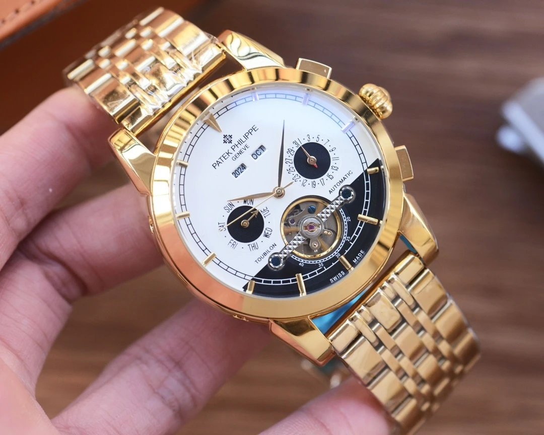 Gold wristwatch with detailed face held by a hand on a wooden surface