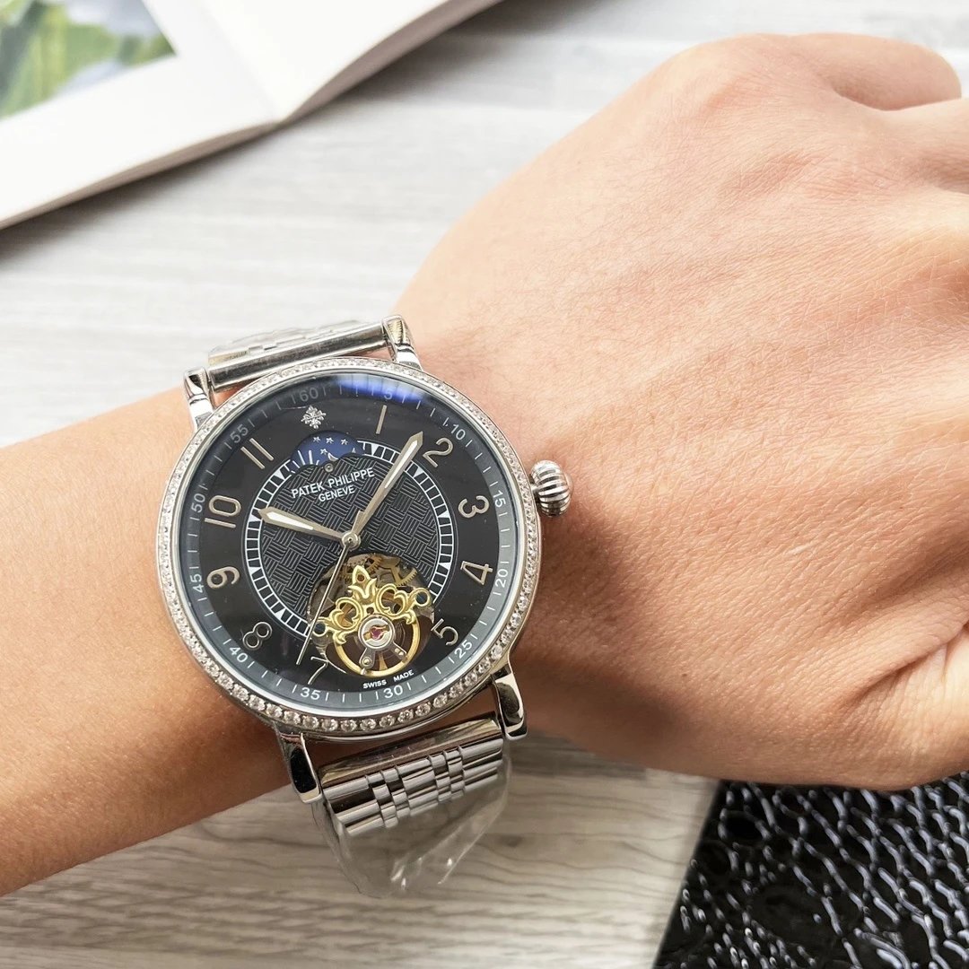 Close-up of a person's wrist wearing a silver and black watch with a detailed face.