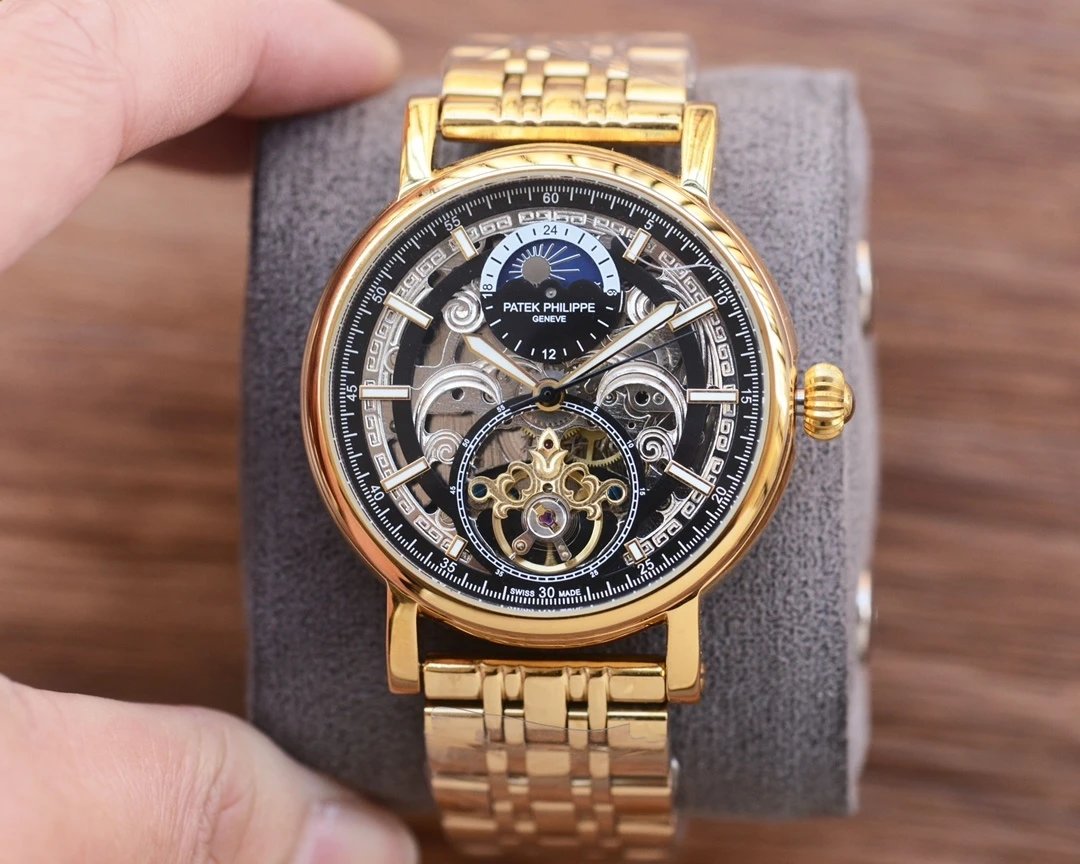 Gold wristwatch with intricate design held by a hand on a wooden surface