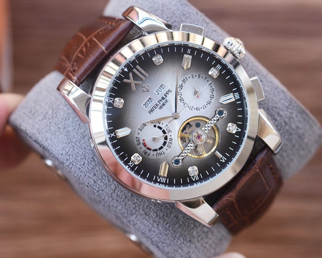 Luxury watch with brown leather strap and detailed face held on a gray surface.