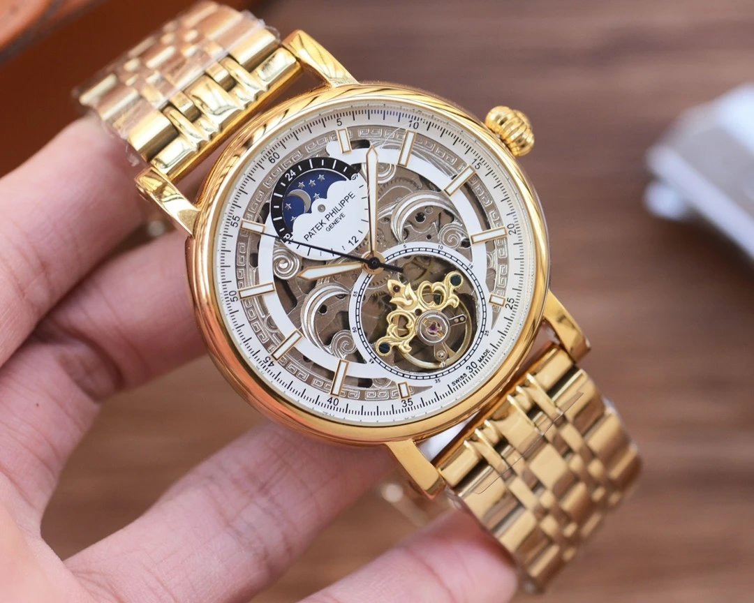 Gold wristwatch with intricate design held in a hand against a blurred background