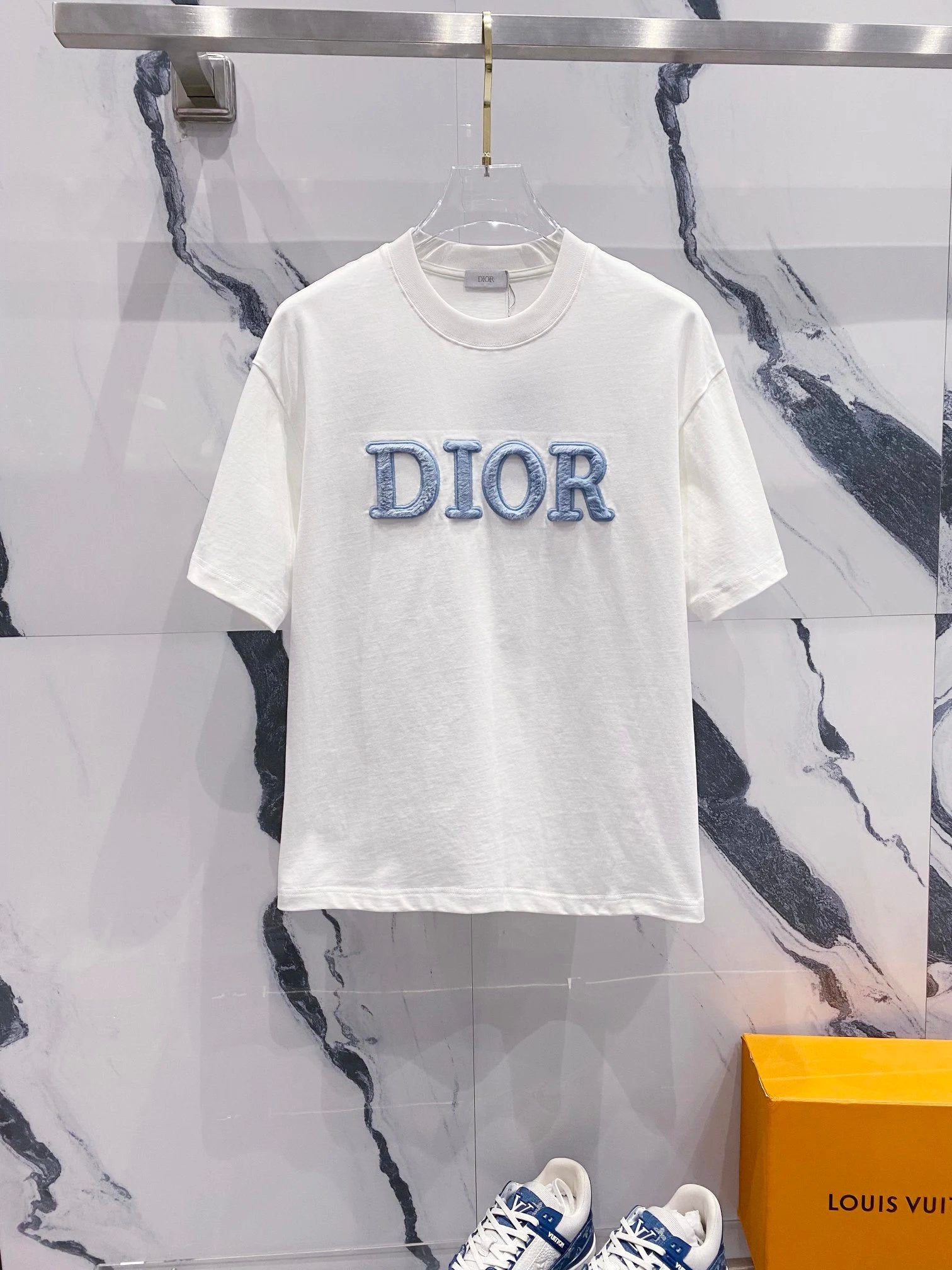 White t-shirt with 'Dior' logo on a marble wall background