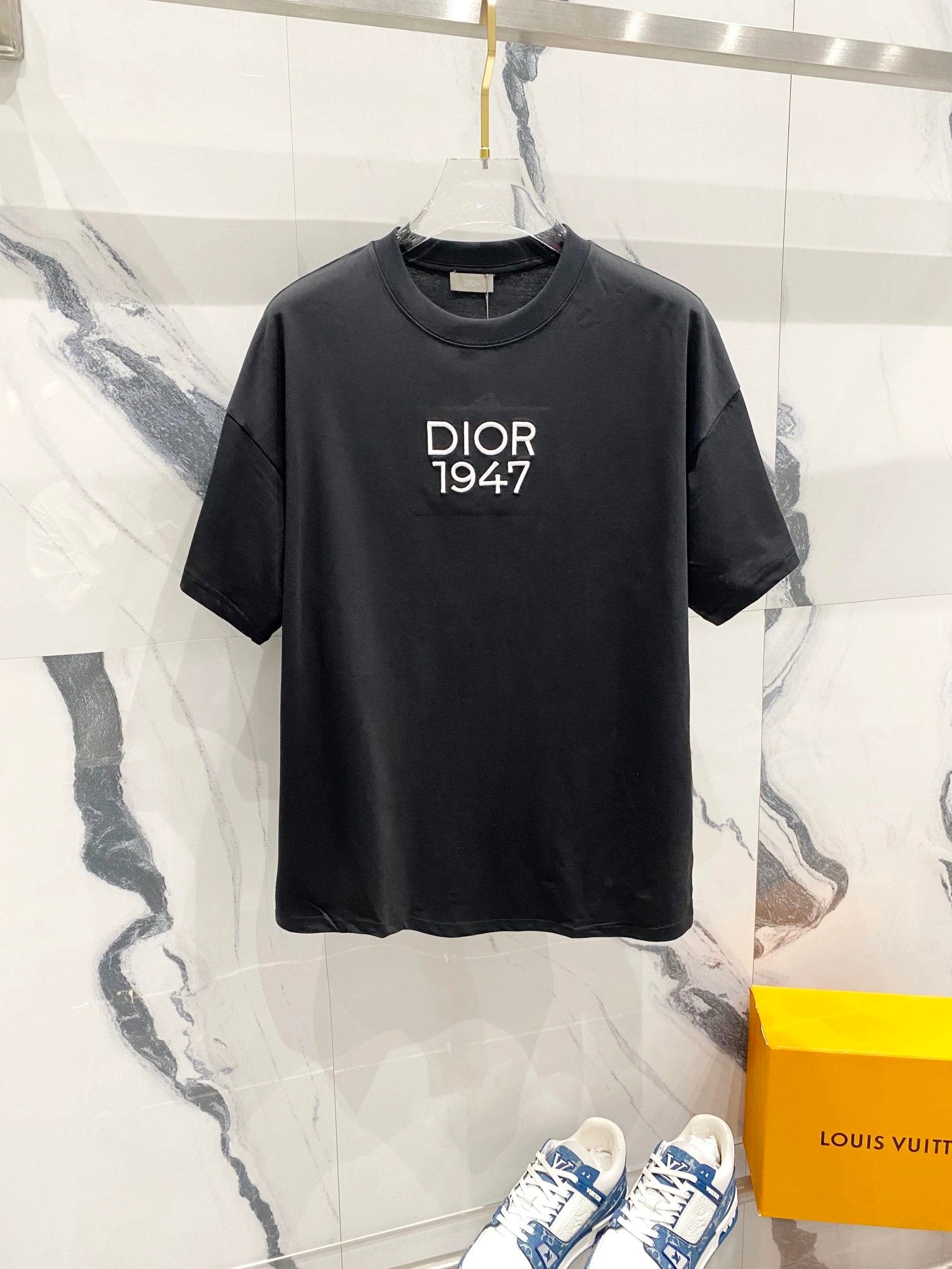 Black t-shirt with 'Dior 1947' text on a marble background
