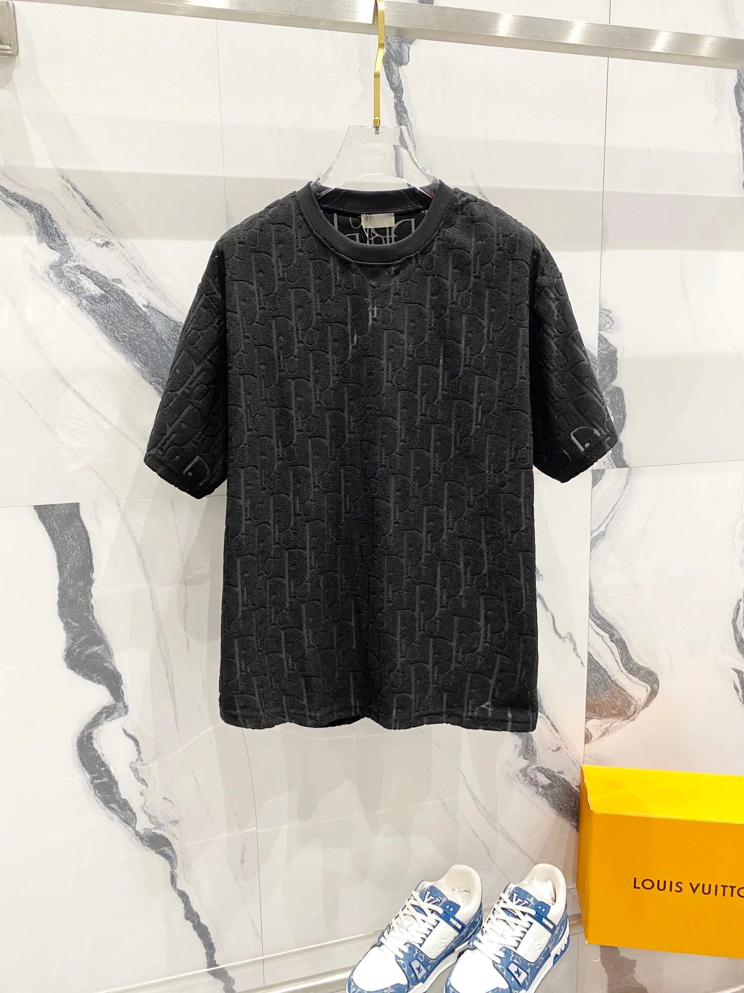 Dark patterned t-shirt on a hanger with a Louis Vuitton box in the background