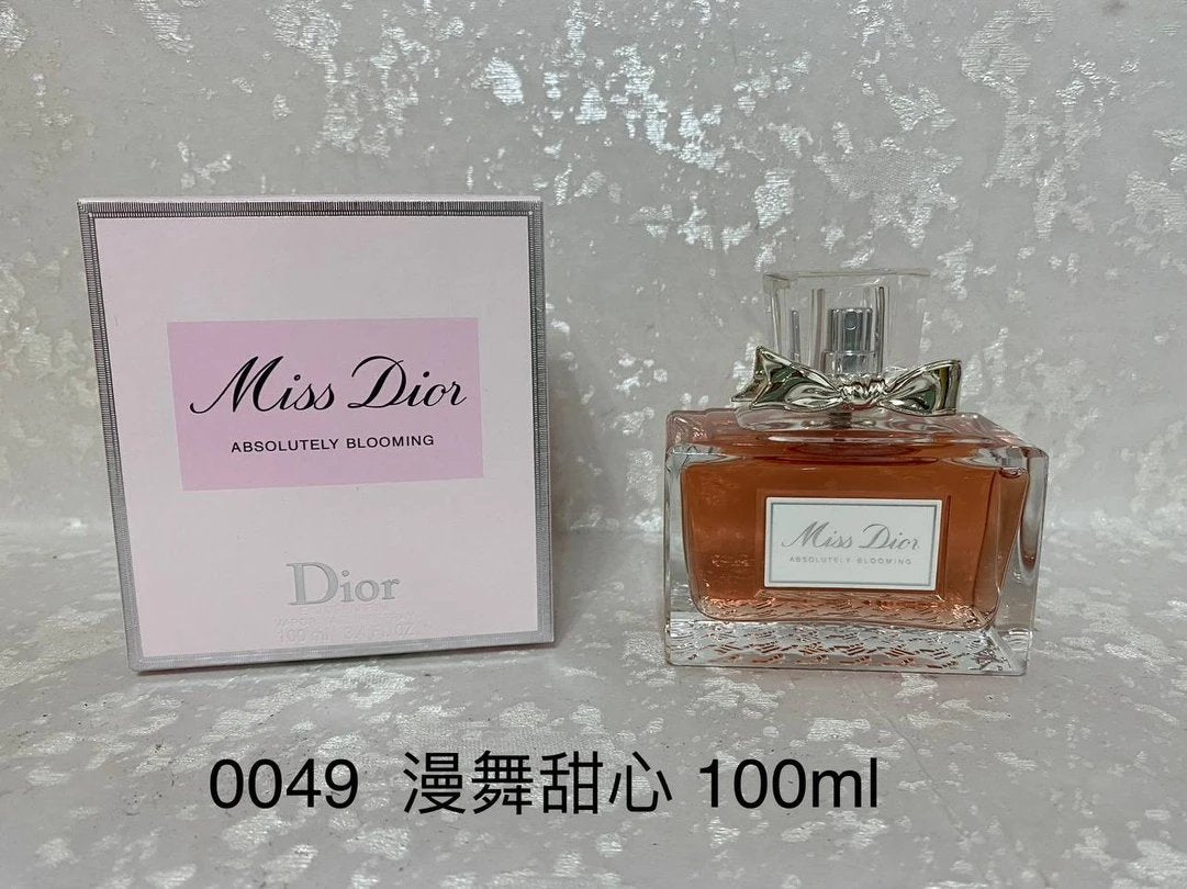 Dior Miss Dior Absolutely Blooming perfume bottle and packaging on a textured gray background