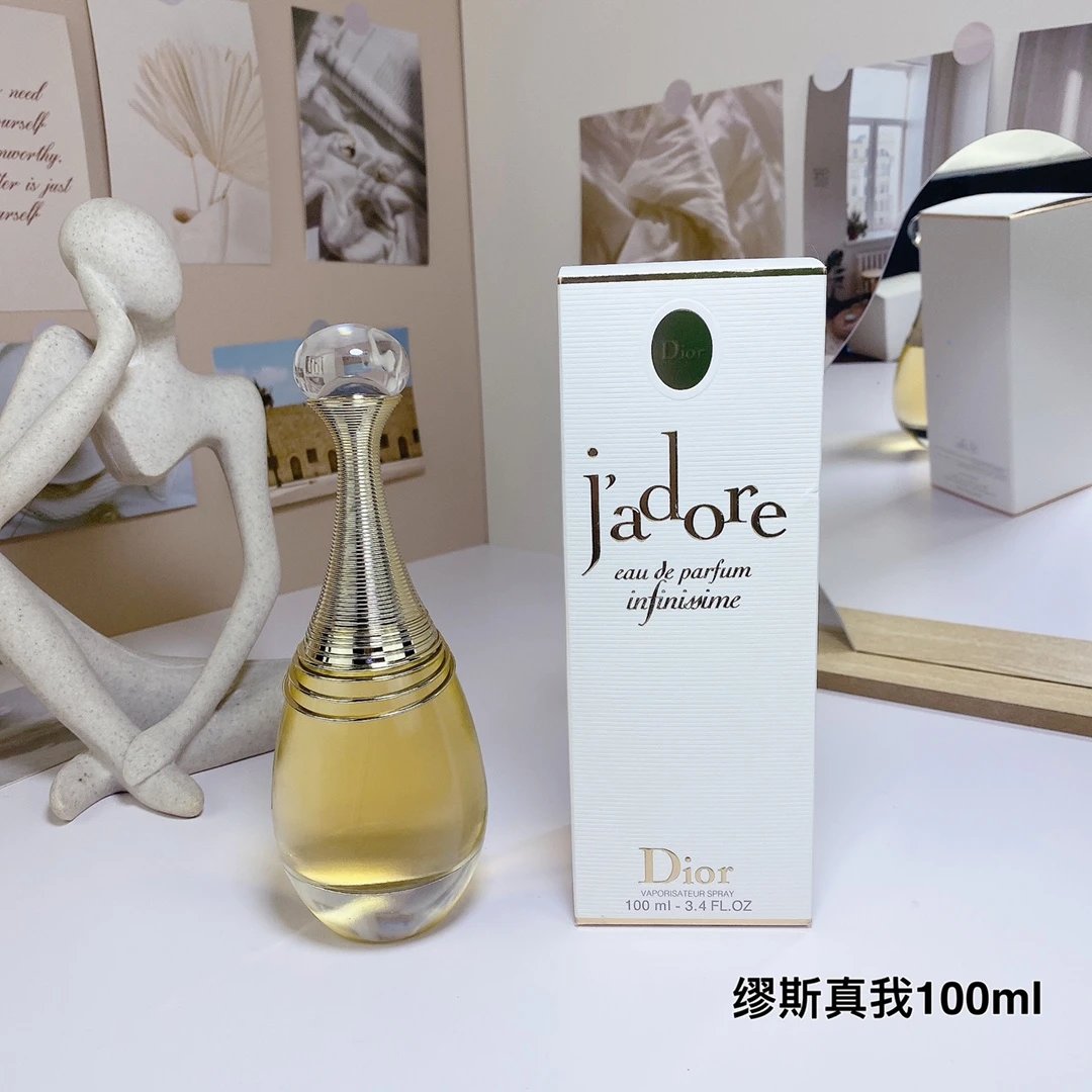 Dior j'adore perfume bottle and packaging on a table with decorative items in the background