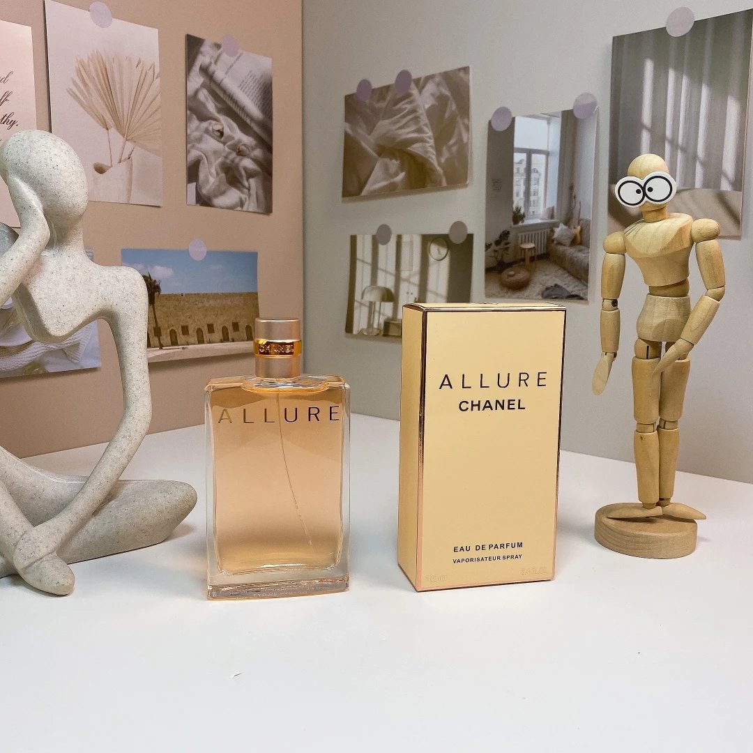 Chanel Allure perfume bottle and packaging on a table with decorative items.