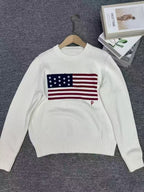 White sweater with American flag design on a hanger against a gray background