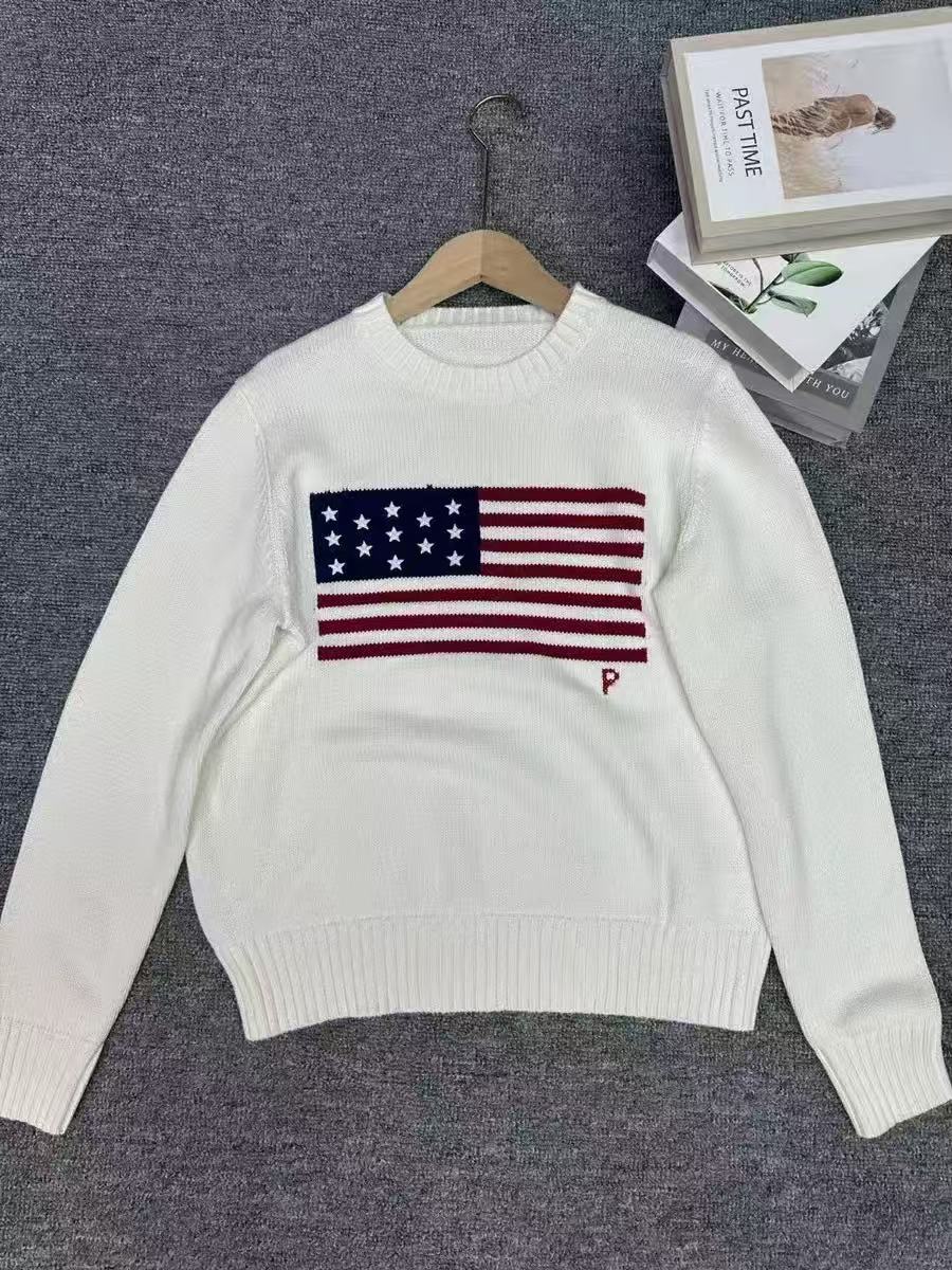 White sweater with American flag design on a hanger against a gray background