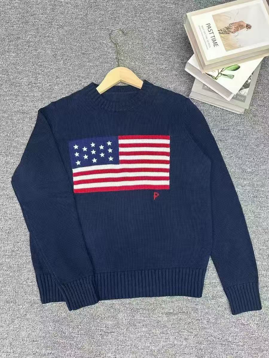 Navy blue sweater with American flag design on a gray surface