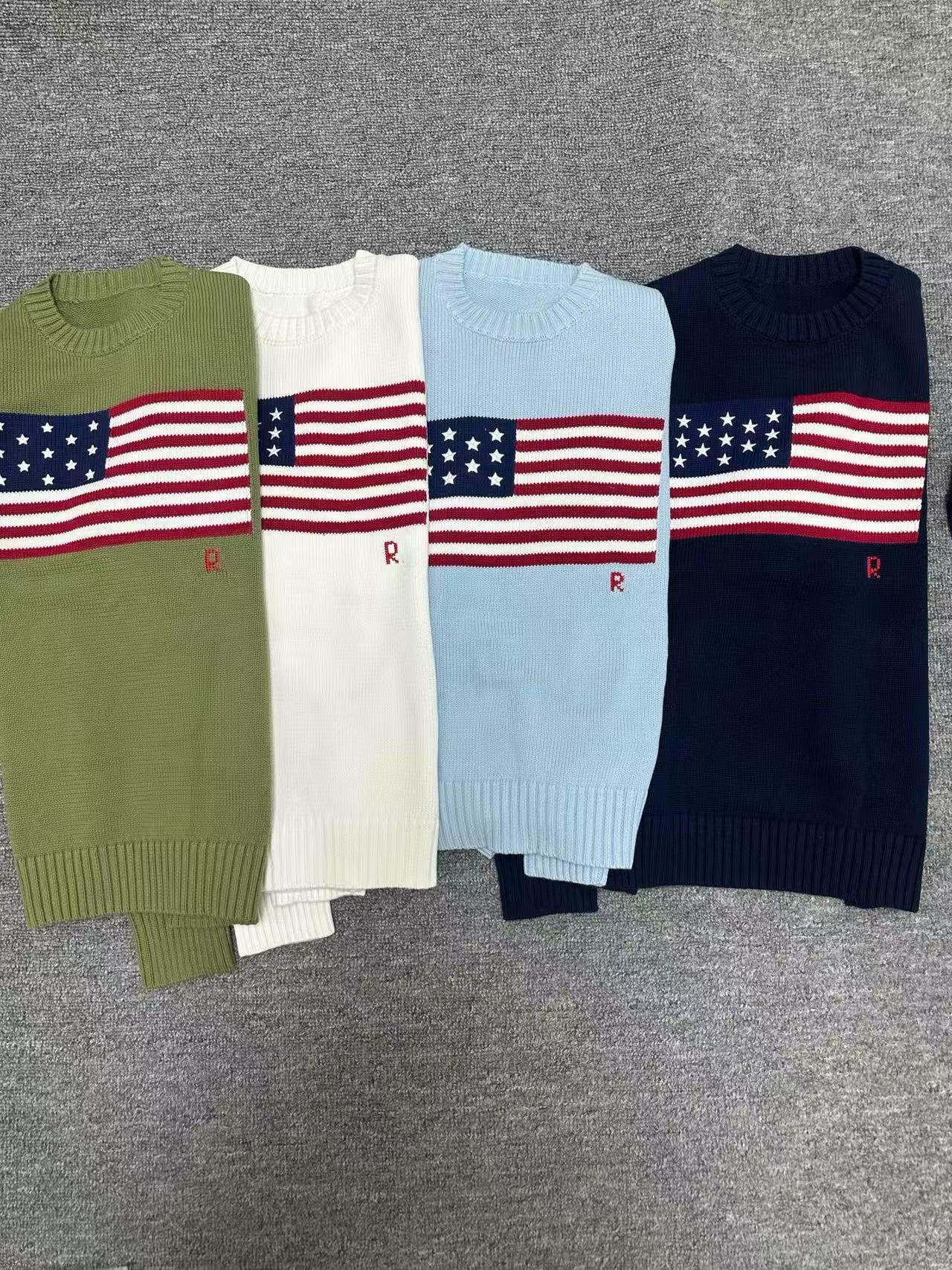 Four sweaters with American flag design on a gray surface