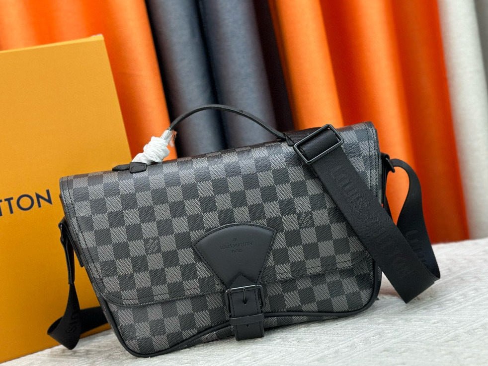 Gray checkered bag with black strap on a surface with orange and gray fabric background