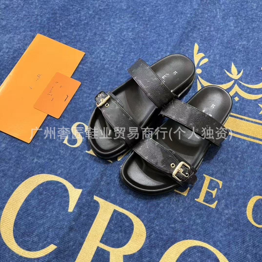 Black sandals with a gold buckle on a blue surface with yellow text