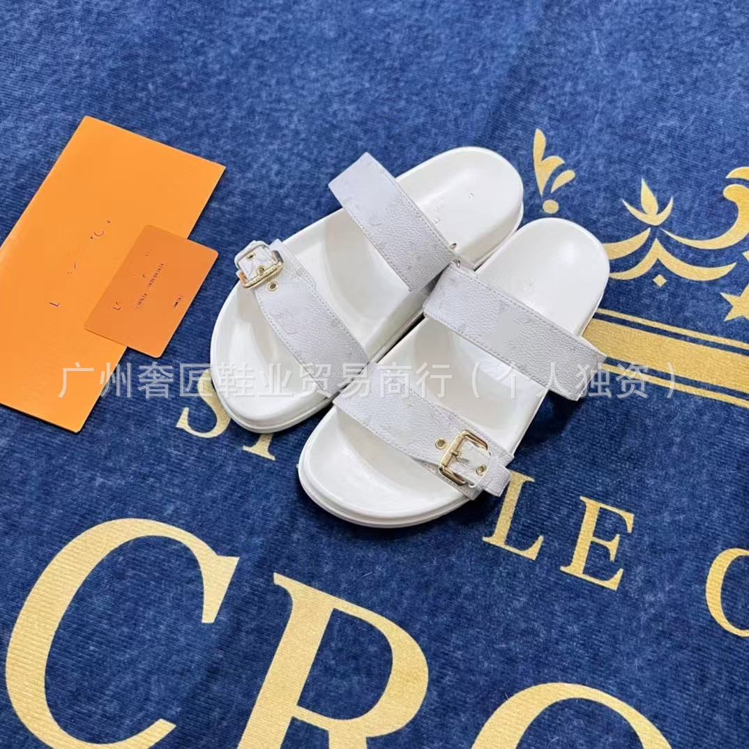 White sandals with gold buckles on a blue surface with gold text