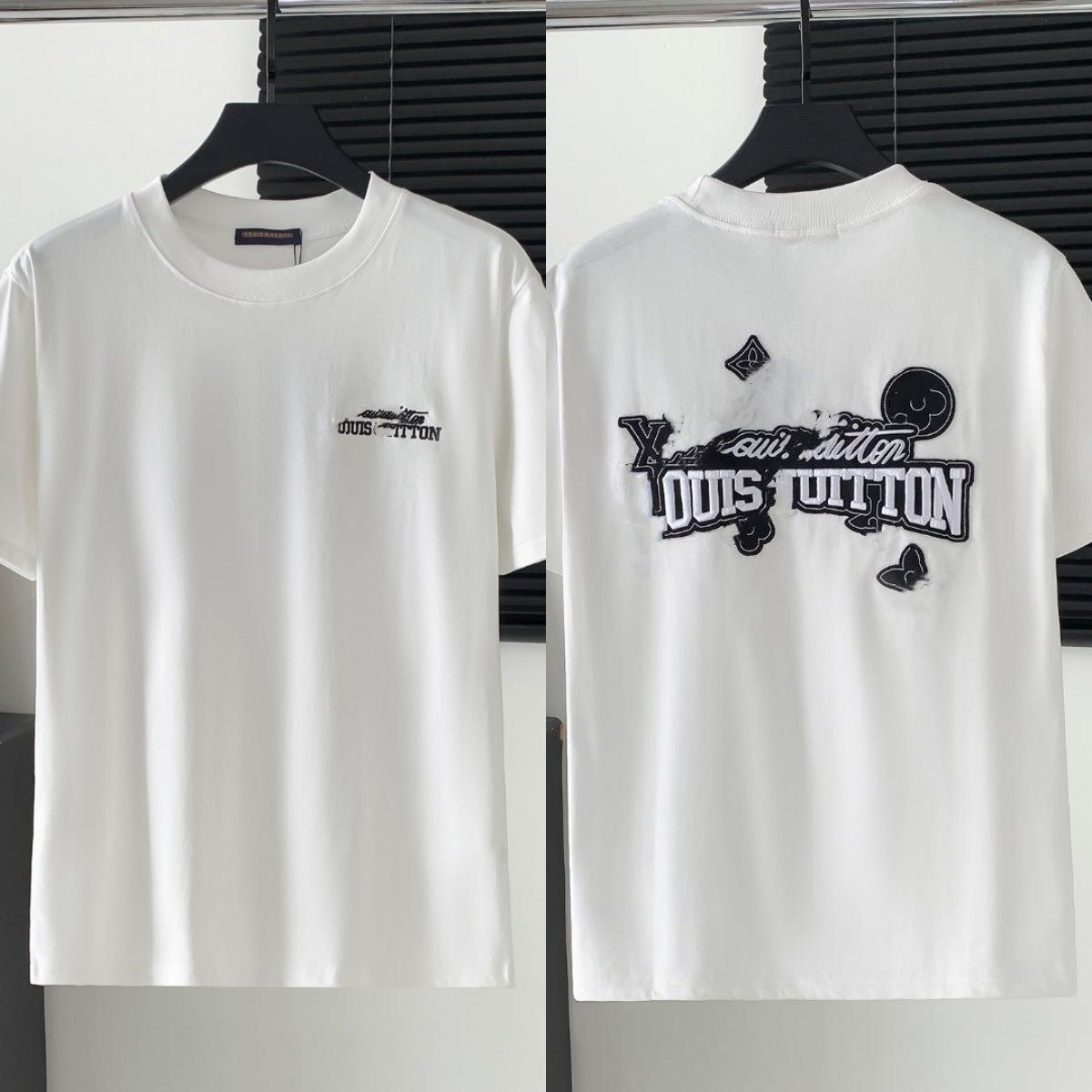 White t-shirt with black embroidered design on a hanger against a neutral background