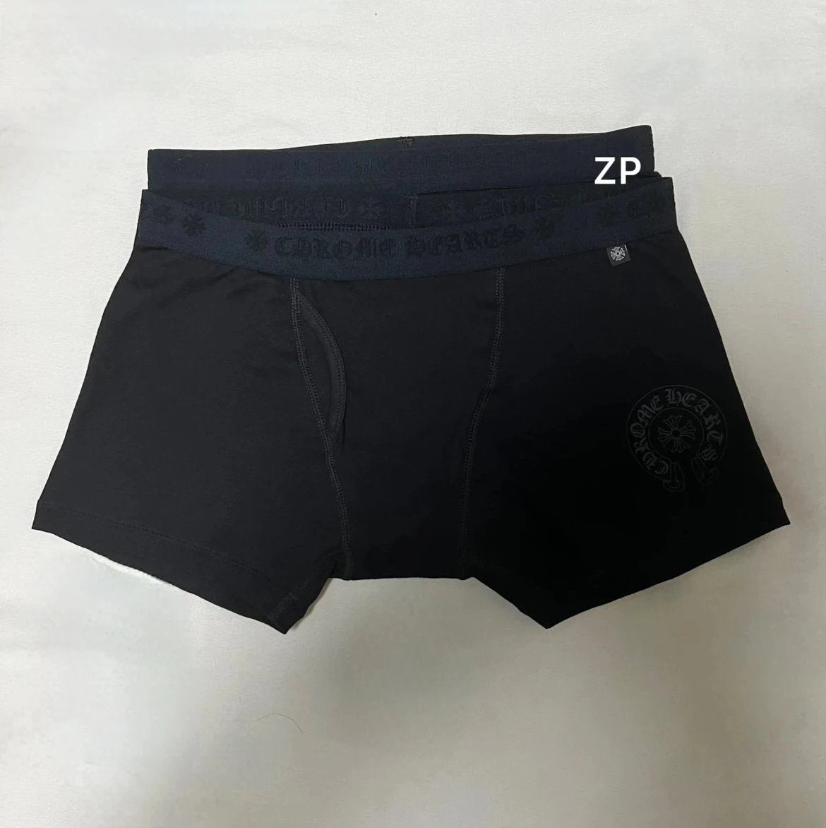Black boxer briefs with a dark waistband featuring the brand name 'CULTURE ARTS' in tonal lettering, laid flat on a light background. A small circular logo is visible on the lower right leg, and a white 'ZP' text overlay is present near the waistband.