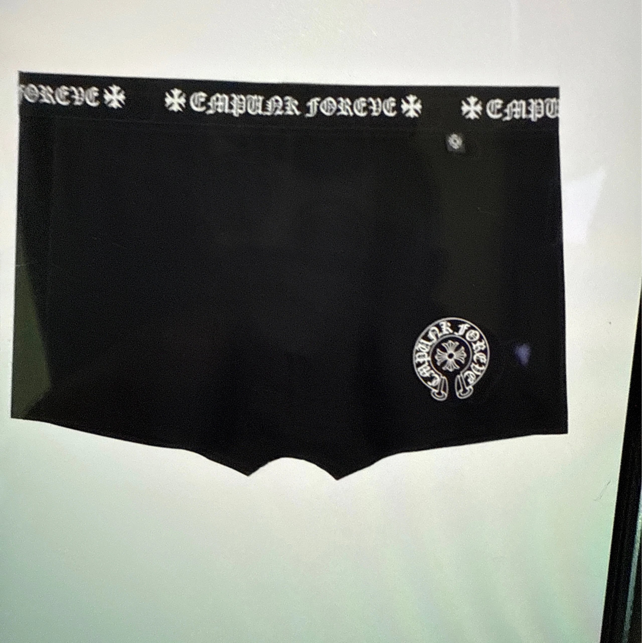 Black boxer briefs with a white Goth-style 'CAPULET FOREVER' patterned waistband and a matching white circular logo patch on the lower right leg.