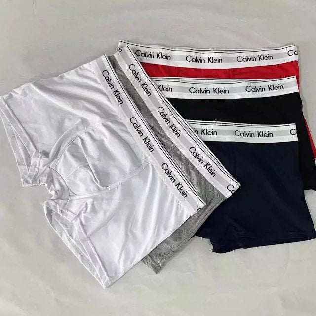 Calvin Klein underwear in white, gray, and black with red and blue waistbands on a light gray background.