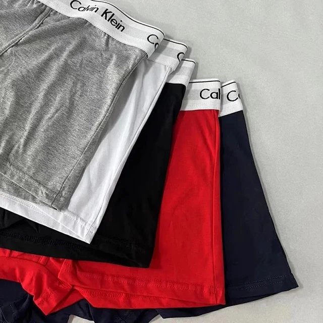 Stack of Calvin Klein boxer briefs in various colors on a gray background